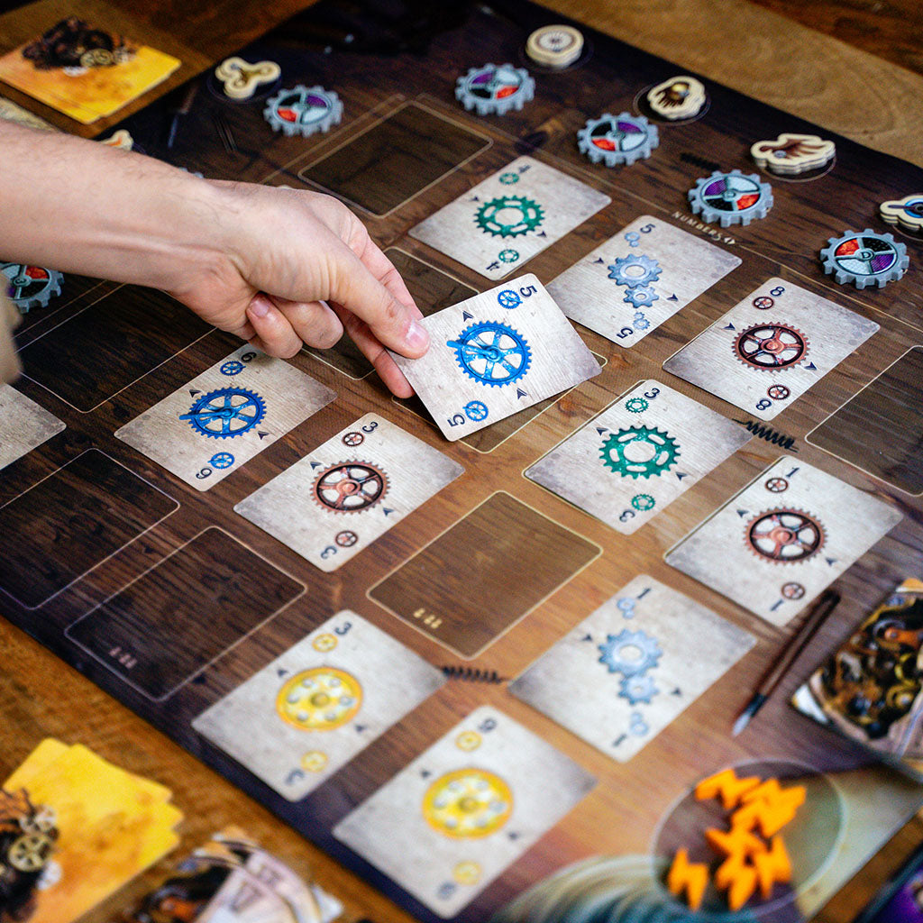 Person playing gear card into grid during game of Gearworks