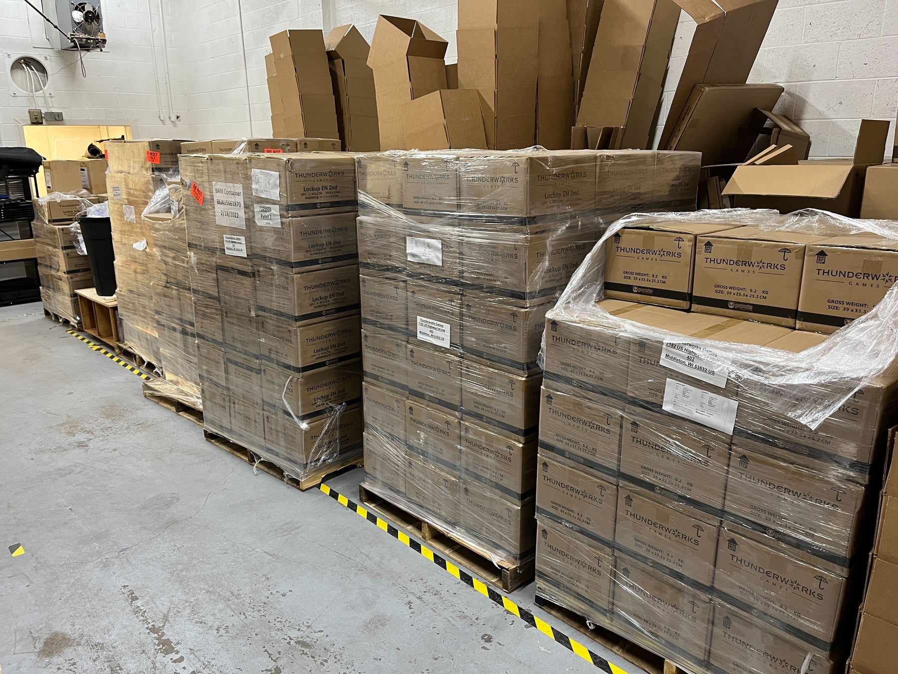 Wooden pallets stacked with cases of board games in a warehouse